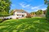 Expansive backyard featuring a large grass lawn, a paved stone patio, an elevated wooden deck, and perimeter privacy fencing