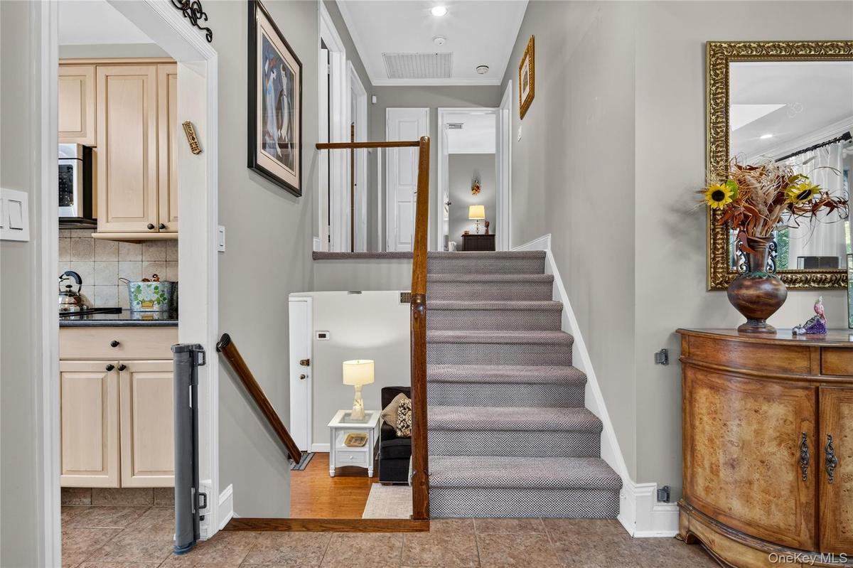 Entryway featuring a carpeted staircase with a wood handrail, ceramic tile flooring, and integrated recessed lighting