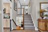 Entryway featuring a carpeted staircase with a wood handrail, ceramic tile flooring, and integrated recessed lighting