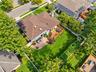 Backyard featuring an elevated wood deck, a brick patio, a manicured lawn, perimeter fencing, and mature trees