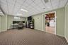 Finished interior space featuring patterned wall-to-wall carpeting, paneled walls, a drop ceiling with recessed lighting, and a sliding door entry
