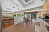 Kitchen featuring ceramic tile flooring, built-in light-finish cabinetry, dark solid-surface countertops, recessed lighting, and a skylight