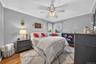Neutral-toned walls, wood-finish flooring, crown molding, and a central ceiling fan with an integrated light fixture