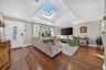 Vaulted ceiling featuring a large rectangular skylight, wood-finish flooring, recessed lighting, and a front entry door with decorative glass paneling