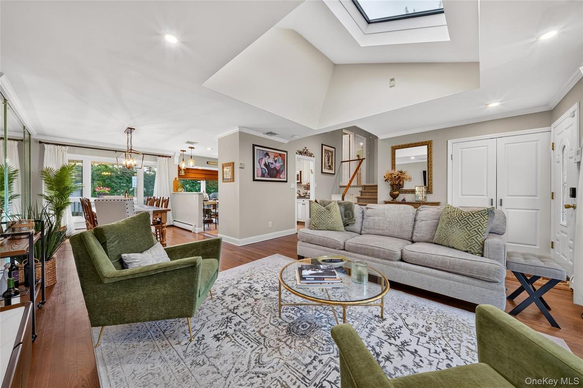 Vaulted ceiling featuring a large central skylight, recessed lighting, and wood-finish flooring