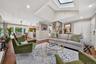 Vaulted ceiling featuring a large central skylight, recessed lighting, and wood-finish flooring