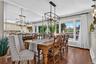 Dining area featuring wood-finish flooring, floor-to-ceiling mirrored wall paneling, crown molding, and a geometric metal pendant chandelier
