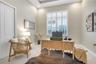 Dedicated home office featuring a tray ceiling, plantation shutters, and natural light.