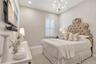 Beautifully appointed bedroom featuring a crystal-style chandelier and plantation shutters.
