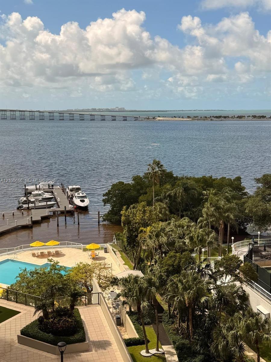 Waterfront property featuring a private boat dock, swimming pool with a paved deck, extensive landscaping with palm trees, and an expansive bay expans