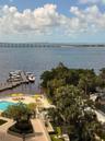 Waterfront property featuring a private boat dock, swimming pool with a paved deck, extensive landscaping with palm trees, and an expansive bay expans
