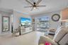 Living area featuring large-format tile flooring, a multi-blade ceiling fan with integrated lighting, crown molding, and sliding glass doors opening t