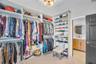 Custom built-in closet organization system with floor-to-ceiling shelving, tiered hanging rods, light-finish cabinetry, and a flush-mount drum ceiling
