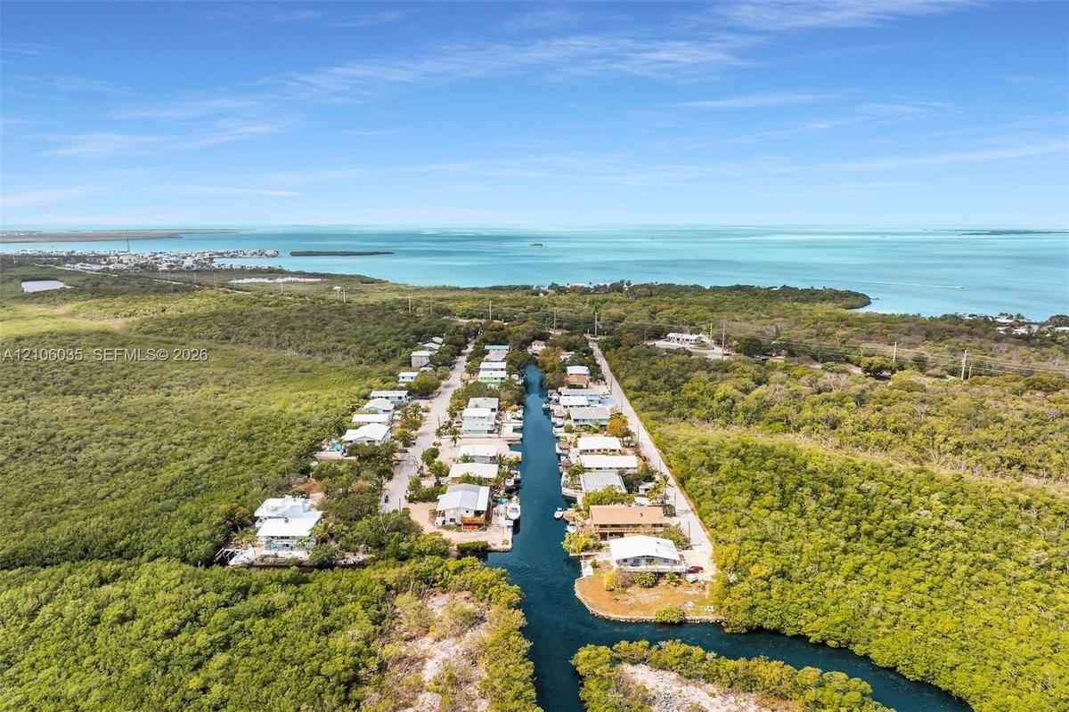 Aerial perspective of a coastal residential community featuring direct canal access, deep-water frontage, and immediate proximity to the open ocean