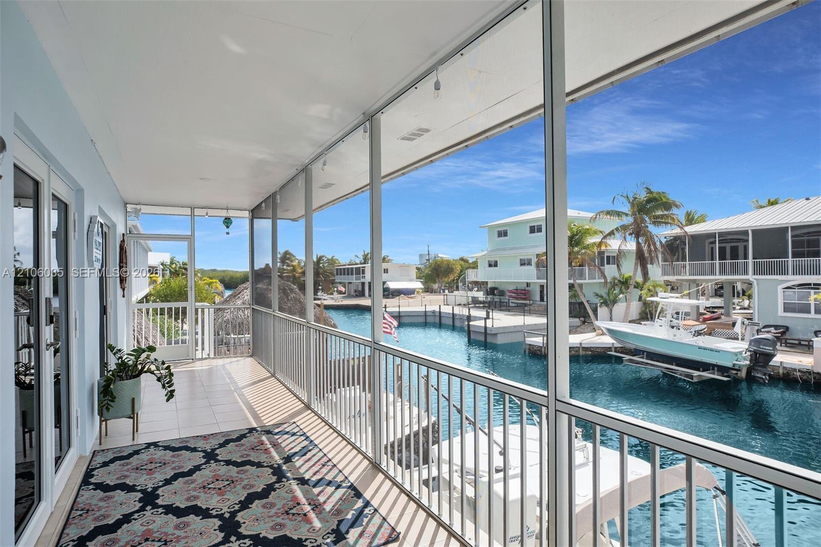 Screened-in balcony featuring tile flooring, metal railings, and direct water canal access