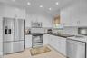 Kitchen featuring white shaker cabinetry, dark stone countertops, stainless steel appliances, subway tile backsplash, and recessed ceiling lighting