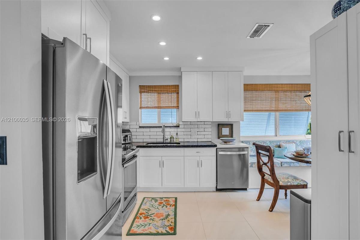 Kitchen featuring white cabinetry, subway tile backsplash, dark solid-surface countertops, recessed lighting, and stainless steel appliances