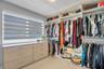 Custom walk-in closet featuring extensive built-in shelving, hanging rods, integrated drawer storage, and a light-filtering window shade