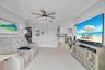 Open living area featuring large-format tile flooring, crown molding, and a modern multi-blade ceiling fan with integrated lighting