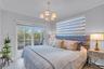 Neutral-toned interior featuring crown molding, large-format tile flooring, five-light chandelier, and glass sliding doors providing external access