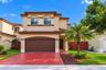 Two-story stucco exterior featuring a clay tile roof, arched architectural detailing, and a multi-car garage
