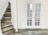 Staircase featuring wood-finish treads and white French doors with glass pane inserts