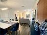 Open-concept interior featuring wood-finish flooring, multi-pendant lighting, and horizontal window blinds