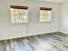 Room featuring wood-finish flooring, dual windows with multi-pane grilles, and horizontal window blinds