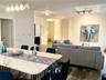 Open-concept interior featuring wood-finish flooring, a contemporary five-pendant linear light fixture, recessed track lighting, and a set of French d