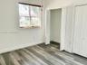 Interior space featuring wood-finish flooring, white walls, horizontal window blinds, and dual bi-fold closet doors