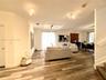 Open-concept interior featuring wood-finish plank flooring, recessed multi-bulb ceiling lighting, and a glass sliding door