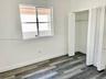 Interior space featuring wood-finish flooring, white walls, a single-pane window, and a built-in closet with multi-panel swinging doors