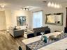 Open-concept interior featuring wood-finish flooring, multi-pendant lighting, track lighting, sliding glass door, and a stone-surface kitchen island