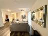Wood-finish flooring, large wall-mounted mirror, multi-light track lighting, and French-style glass panel doors