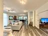 Open floor plan featuring wood-finish flooring, recessed track lighting, double-door entry with glass panes, and stairs with wood-finish treads