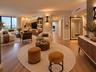 Open-concept living space featuring wood-finish flooring, custom built-in cabinetry with integrated shelving and recessed lighting, floor-to-ceiling w