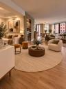Open-concept interior featuring wood-finish flooring, built-in recessed shelving with integrated lighting, a beverage refrigerator, and expansive floo