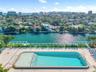 Swimming pool with built-in stairs, large paved patio, and glass railings overlooking a canal
