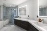 Floating dual-sink vanity with matte dark cabinetry and white countertops, glass-enclosed walk-in shower with textured tile surround, and dual LED-bac