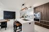 Kitchen featuring a center island with a built-in cooktop, stone-surfaced countertops, high-contrast wood-finish cabinetry, a stainless steel wall ove