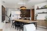 Kitchen featuring high-gloss cabinetry, stone-patterned backsplash, built-in double ovens, large center island, and overhead skylight