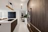 Kitchen featuring full-height wood-finish cabinetry, built-in double wall ovens, a large island with a surface-integrated cooktop, and large-format po