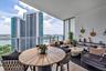 Covered balcony featuring wood-finish tile flooring, glass-panel railings, and panoramic coastal and skyline scenery