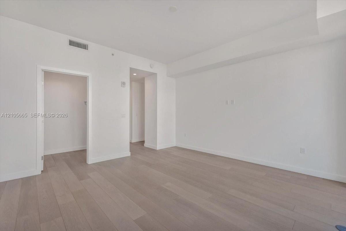 Neutral-toned wood-finish flooring, crisp white walls, and recessed ceiling lighting