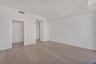 Neutral-toned wood-finish flooring, crisp white walls, and recessed ceiling lighting