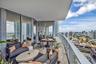 Wraparound balcony featuring large-format porcelain tile flooring, glass panel railings, and floor-to-ceiling glass sliding doors