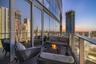 Covered balcony featuring floor-to-ceiling glass walls, wood-finish decking, and a glass-paneled railing