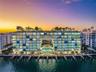 Waterfront mid-rise structure featuring floor-to-ceiling glass paneling, private balconies, and an integrated boat dock system with multiple slips