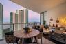 Covered outdoor balcony featuring tile flooring, glass panel railings, and urban skyline scenery