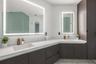 Double vanity featuring dark cabinetry, solid-surface countertops, integrated rectangular sinks, polished chrome faucets, and large backlit mirrors